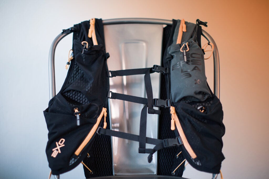 The front of a black Deckers X Lab NVRSTP backpack with pink zippers