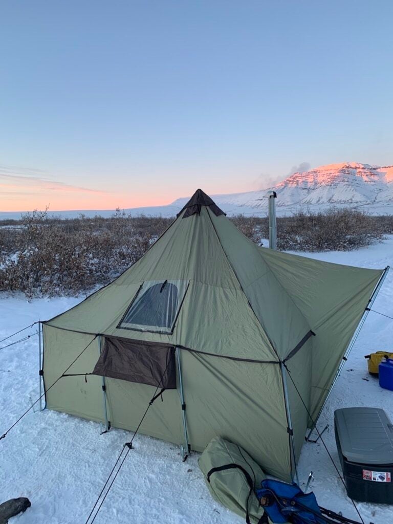 A tall, green tent looking over a snowy mountainscape