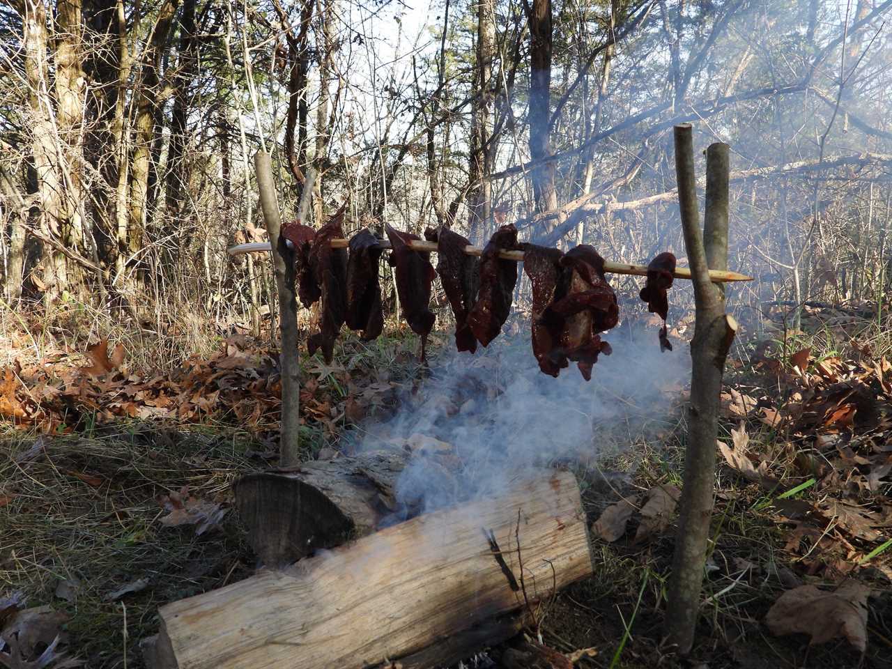 Strips of meat smoking over a fire