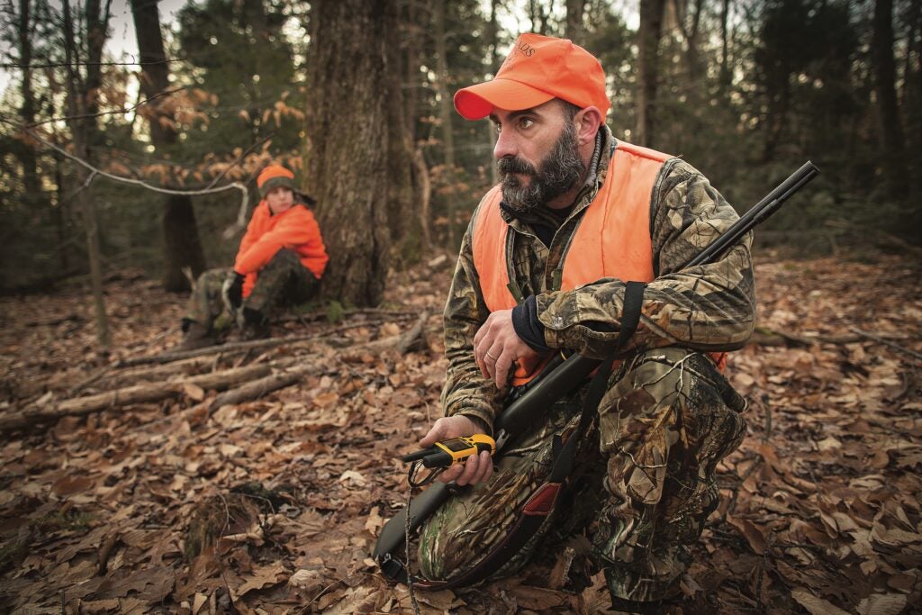 Two hunters crouch on the ground during a deer drive.