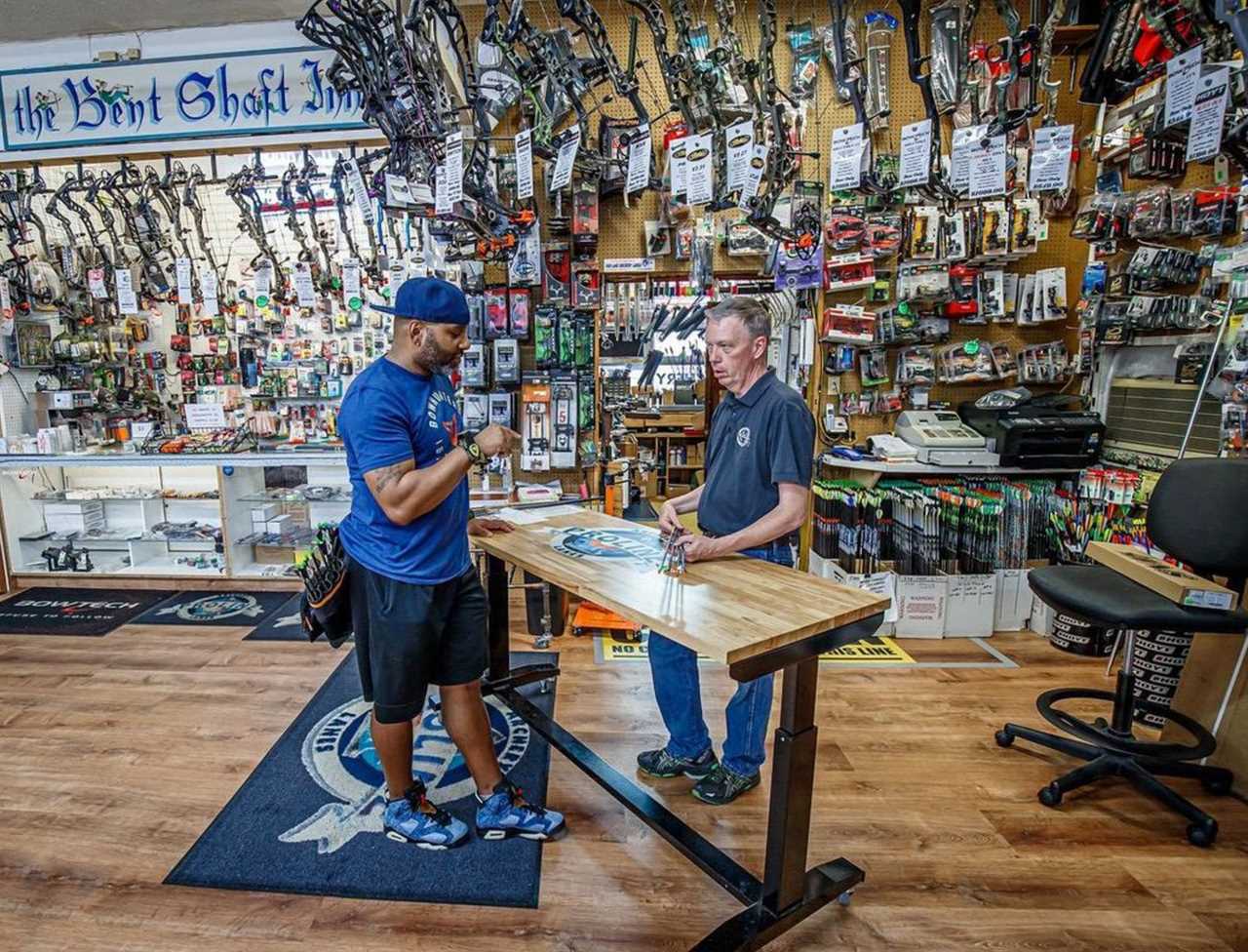 A bowhunter debating arrows with a pro shop employee.