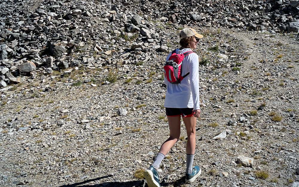 A woman hiking with a small pink backpack