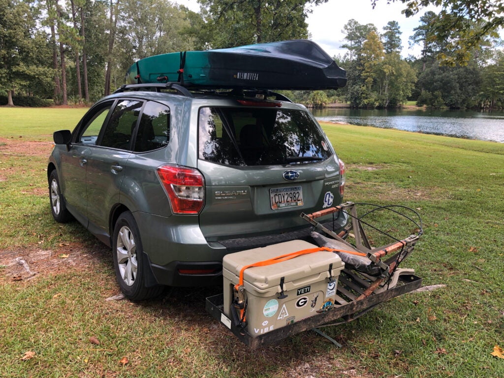 A Subaru Forester with a fishing kayak nad cooler.