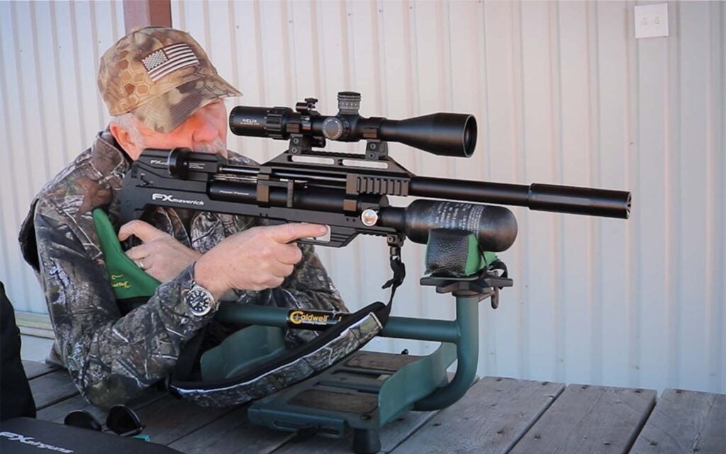 A man wearing camo holding a black air rifle