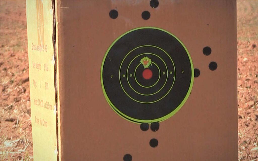 A cardboard box with a black target and bullet holes in it