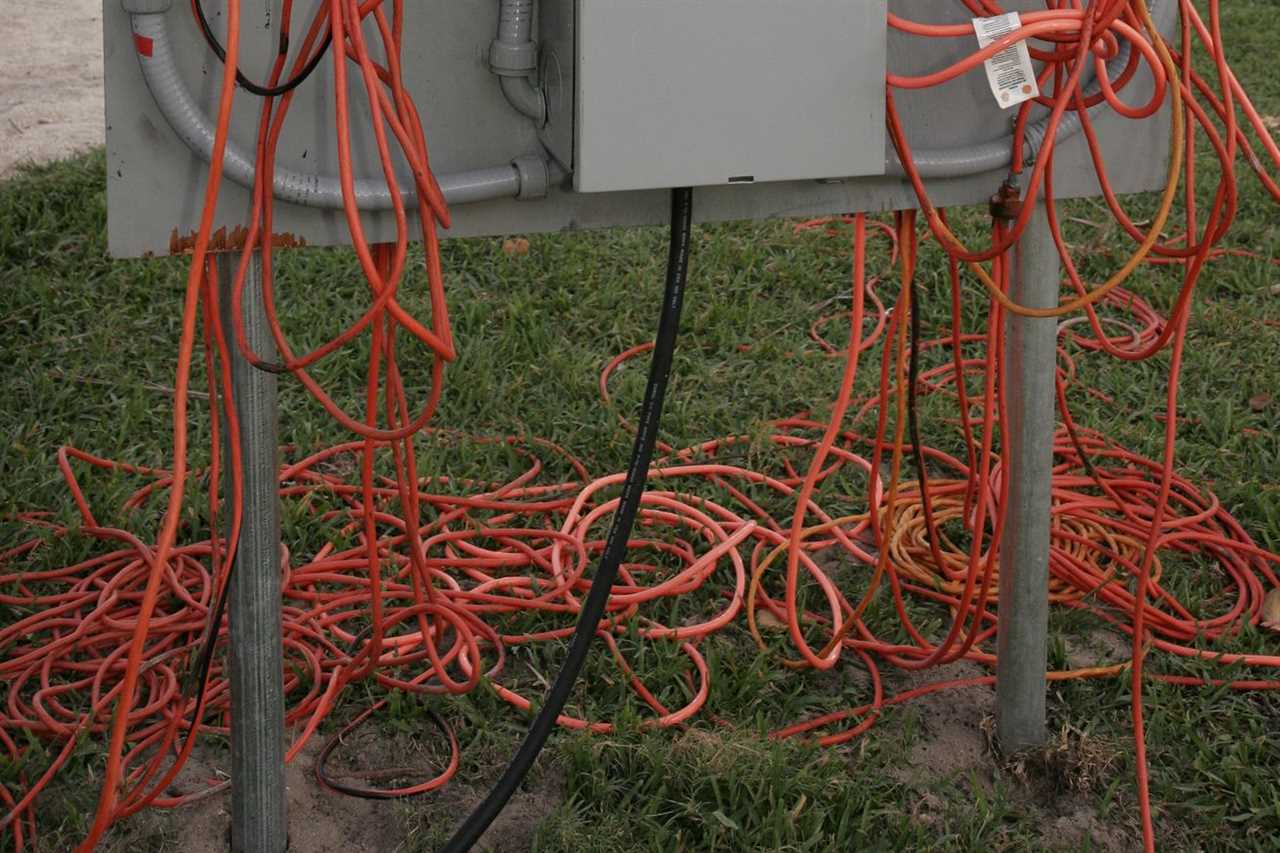 Tangled extension cords under a set of electrical outlets in Lummus Park