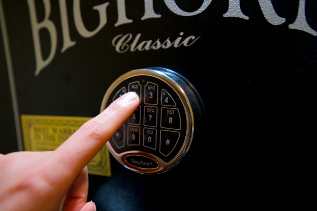 A hand pressing a keypad on the best gun safe.