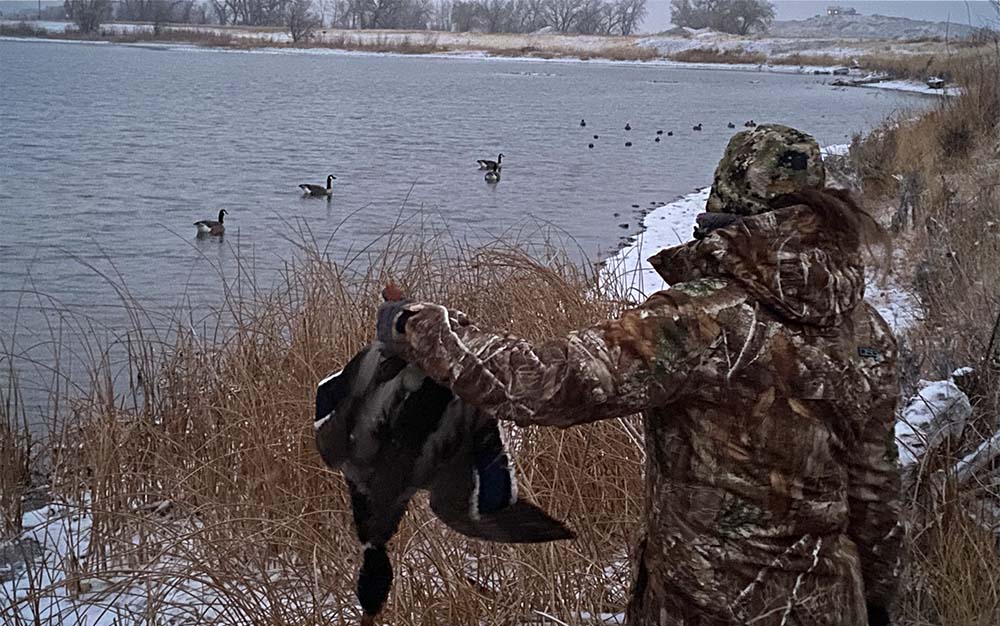 A woman in a camo hooded jacket holding a bird