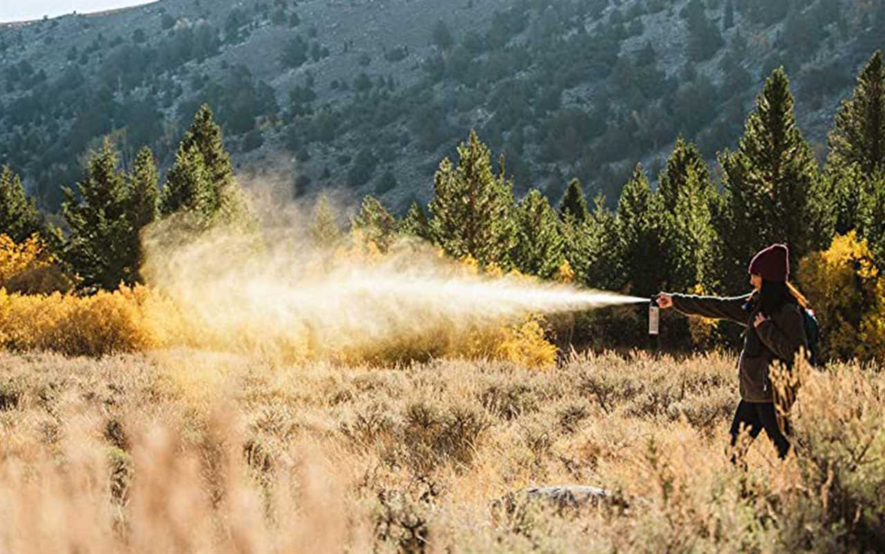 A woman testing bear spray in a field.