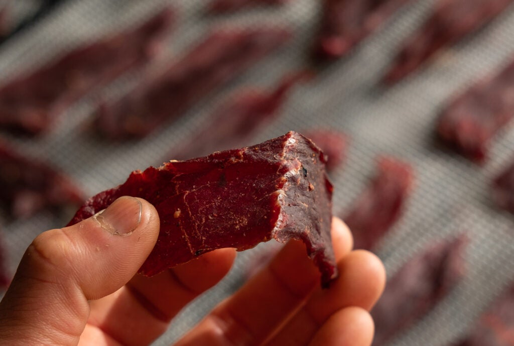 A hand bending a piece if jerky