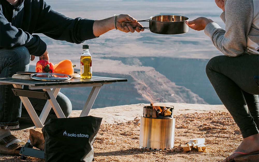 Two people cooking over an open fire stove