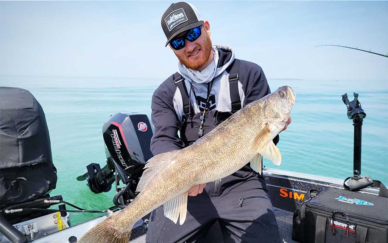 A man holding a walleye on a boat