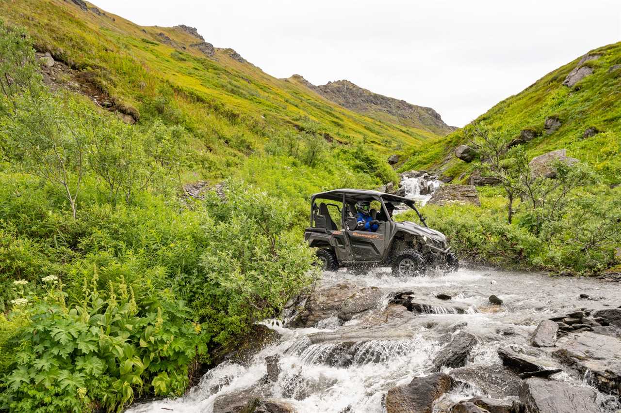 A Wolverine UTV crosses a stream.