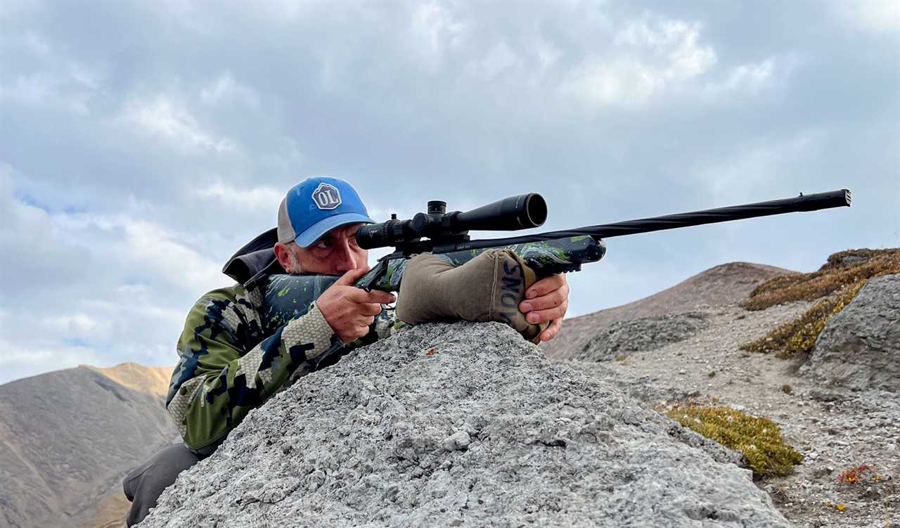 Hunter set up on rifle in the mountains