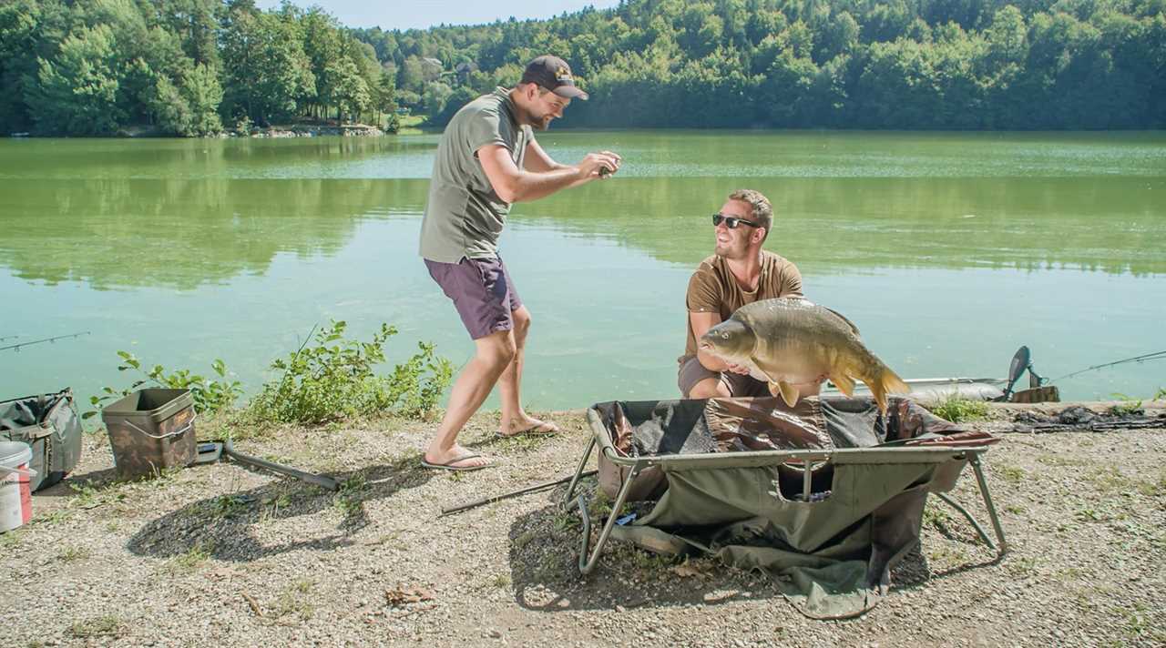 A man takes a photo of his buddy holding up a fish.