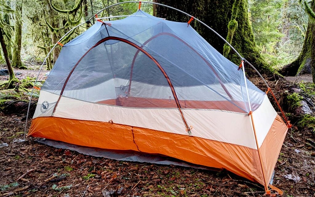 An orange and mesh best backpacking tent in the woods