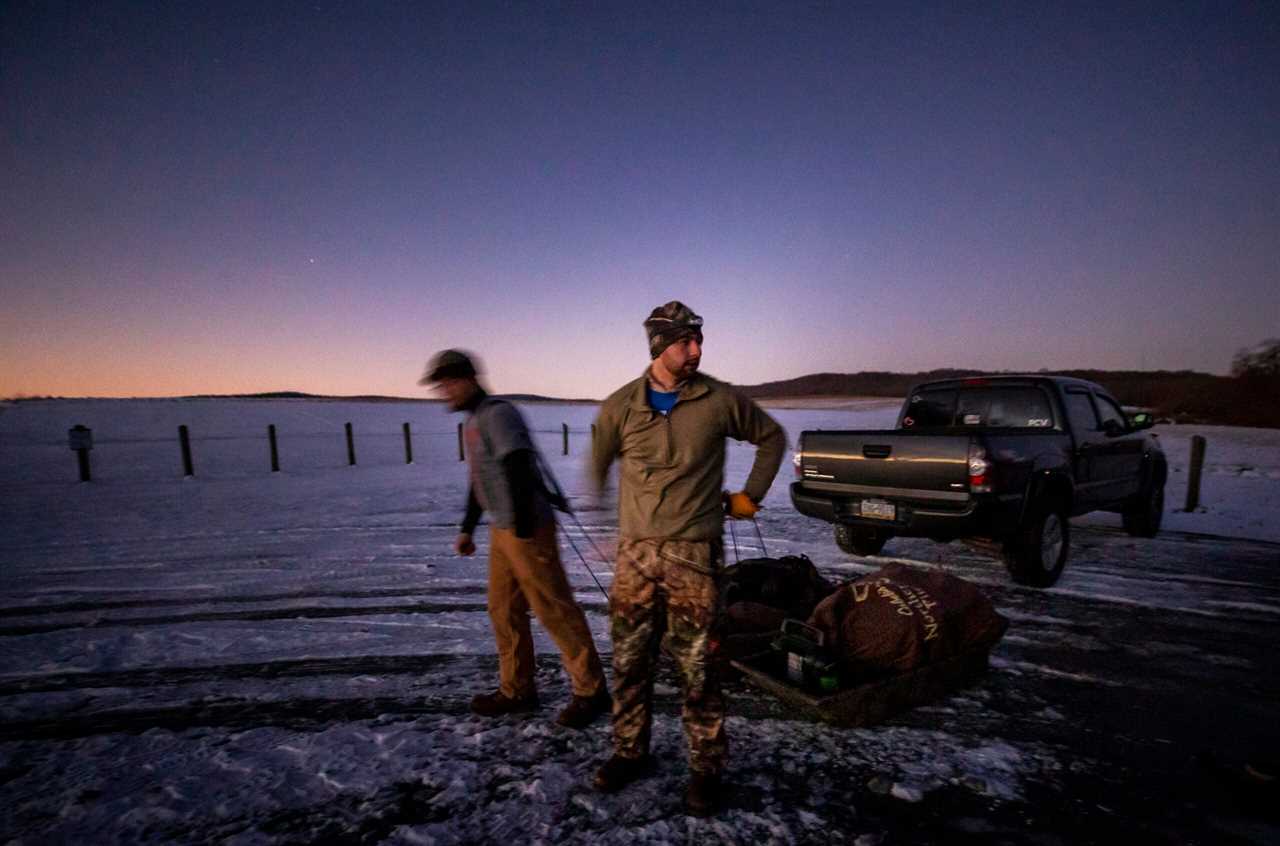 Two hunters drag sleds full of gear onto public ground.