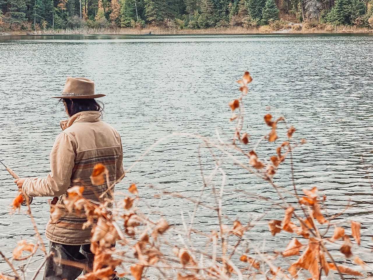 Man in brown clothing wades through a stream.