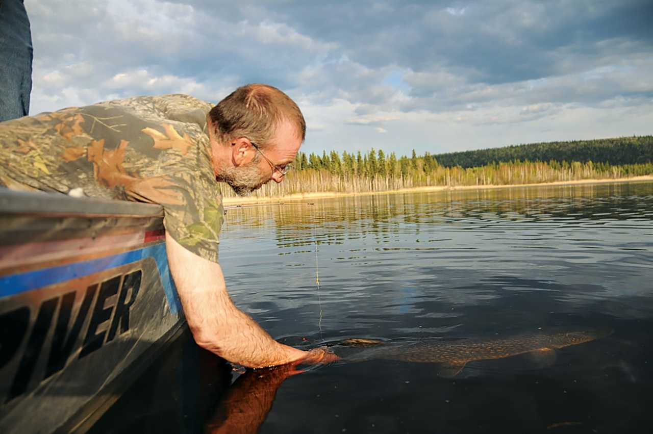 man in boat holds fish by tail underwater