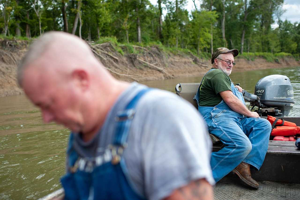 Larry Heavener sits at tiller to steer boat with son Glen in bow.
