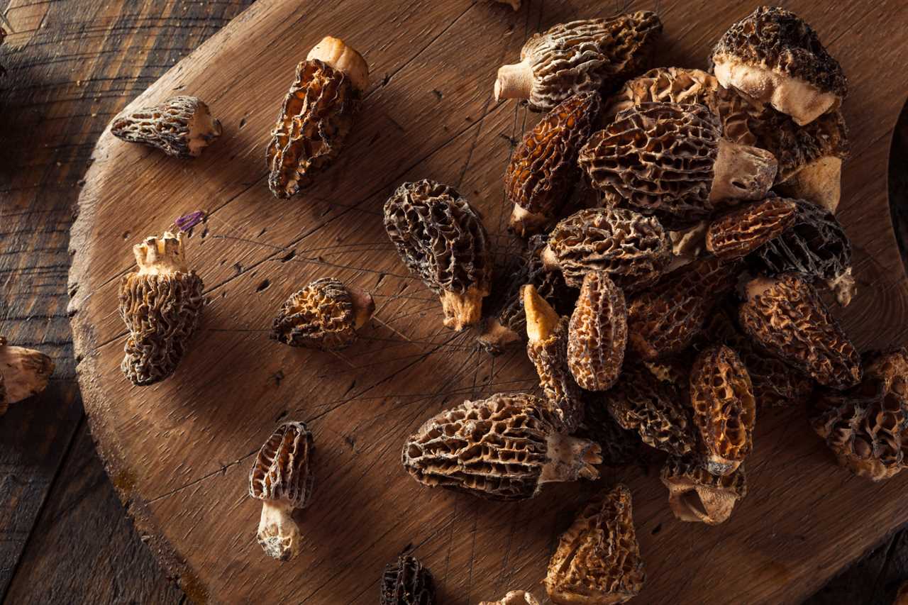 Two dozen morel mushrooms on a cutting board.