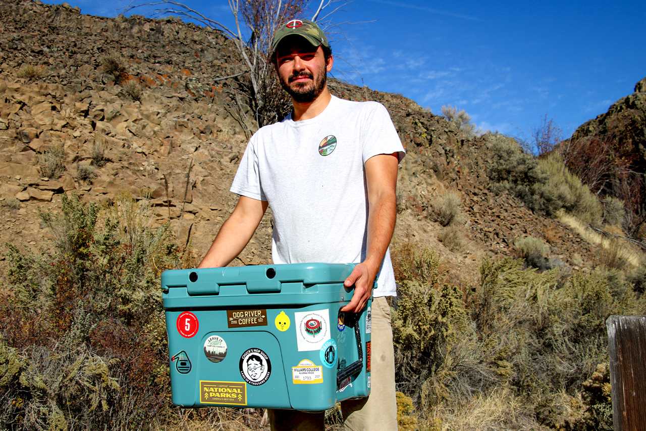 A hunter holds a cooler full of venison.