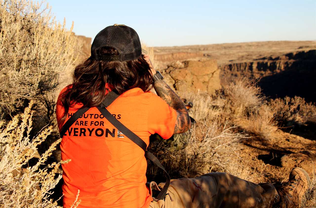 A hunter looks for mule deer through his binoculars.